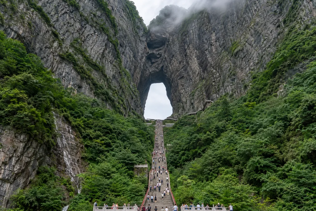 Tianmen Cave, a huge natural arch high in the cliff of Tianmen Mountain, with a long stairway leading up to it