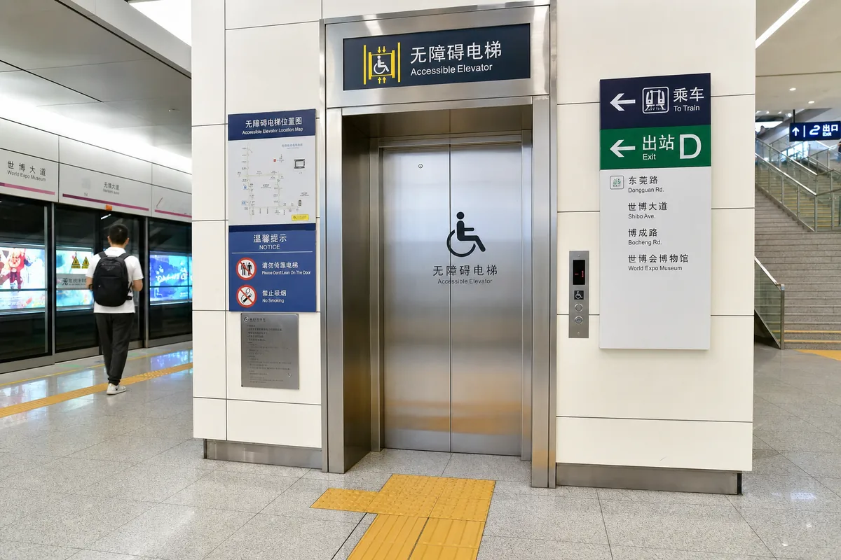 Accessible elevator with wheelchair signage and tactile paving in a Chinese metro station