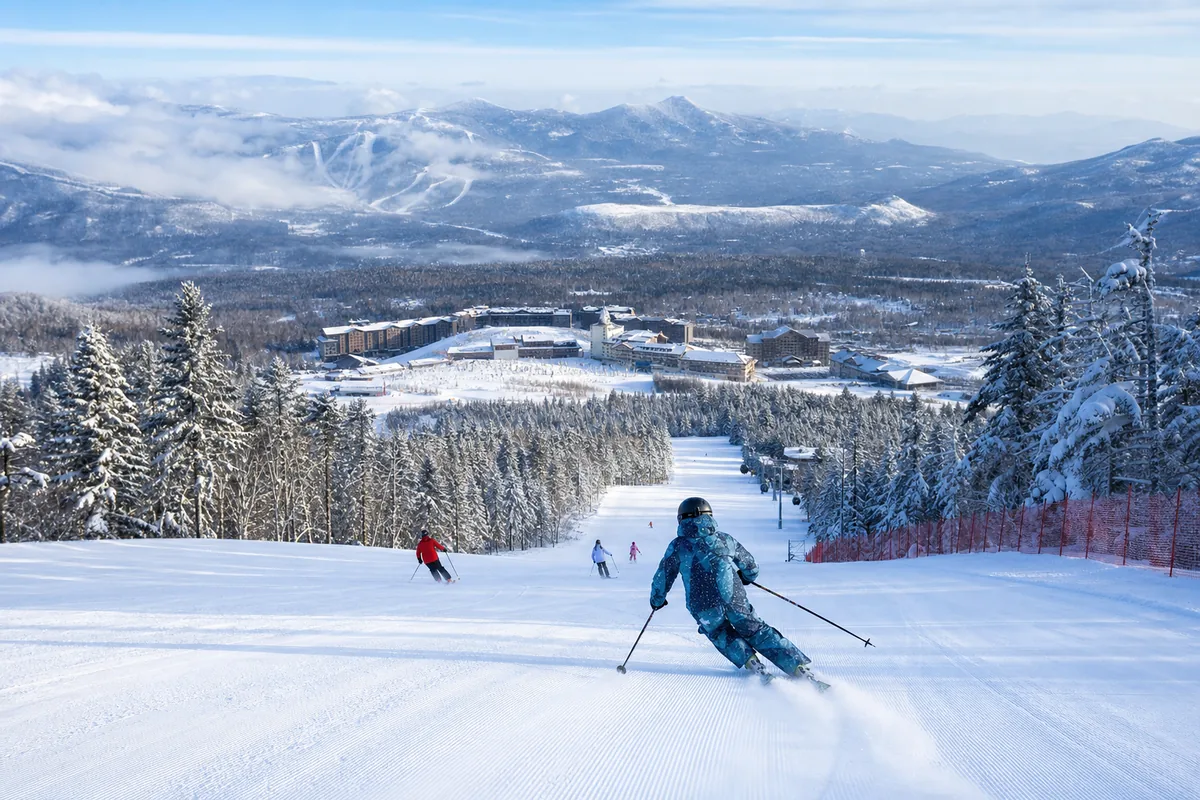 Skiers on groomed runs at the Changbaishan ski resort surrounded by snow-covered forest in winter
