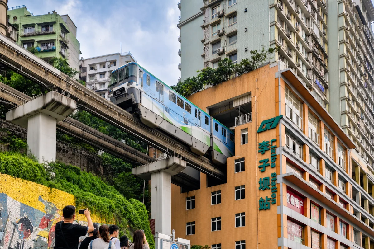 Light rail monorail passing through a residential apartment building at Liziba station in Chongqing