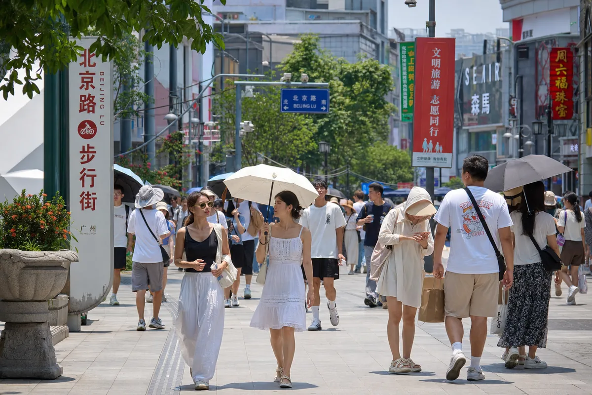 Tourists in light breathable summer clothing with hats and sun umbrellas on a humid southern Chinese city street