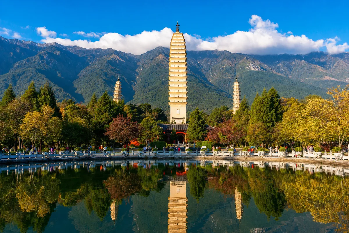The Three Pagodas of Dali reflected in a pond with Cangshan mountains behind