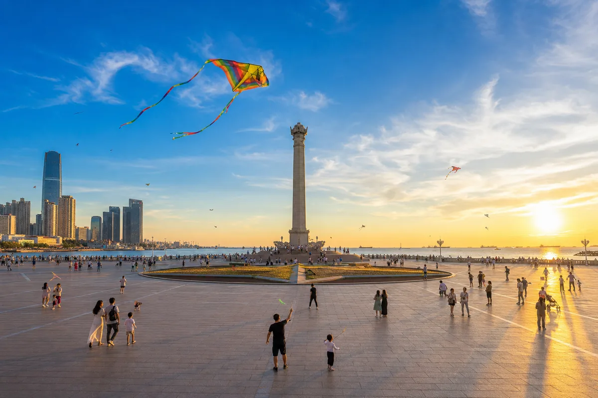 Xinghai Square with its central column and people strolling at sunset