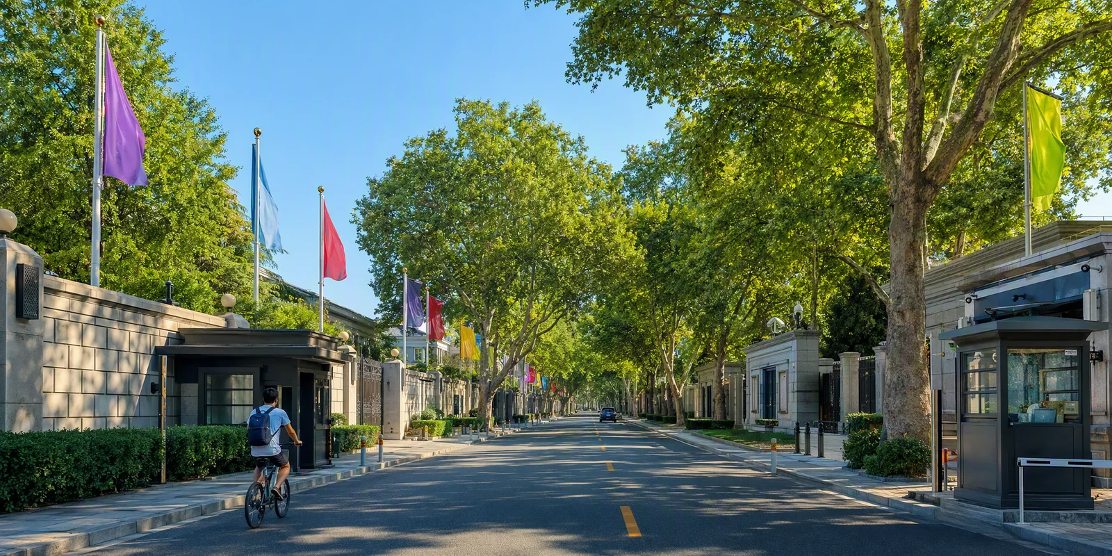 A tree-lined street in Beijing's embassy district with walled compounds and flags on poles