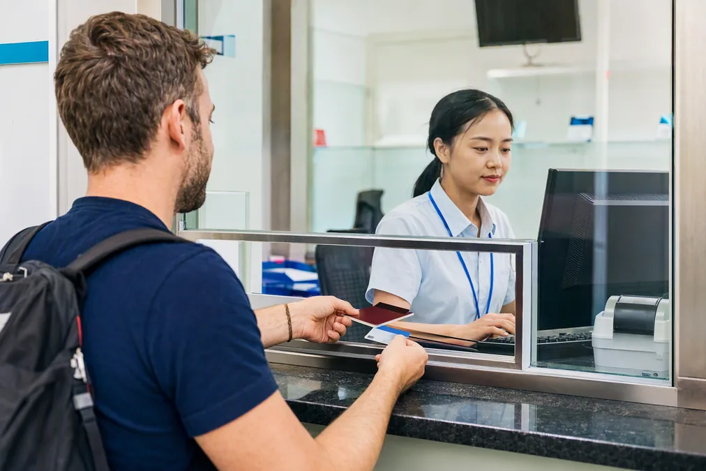 A foreign patient handing a passport and insurance card to a hospital cashier window in China