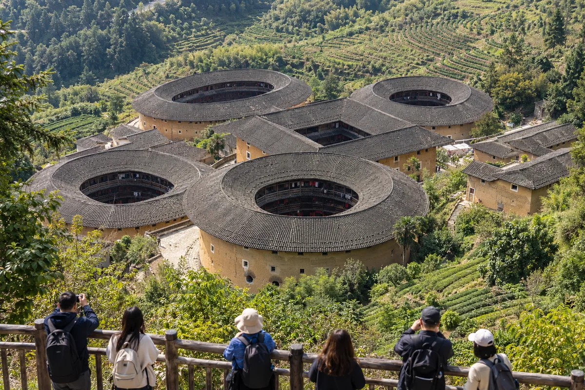Tianluokeng tulou cluster seen from the upper viewing platform: five earthen buildings on a slope in Nanjing County, Fujian