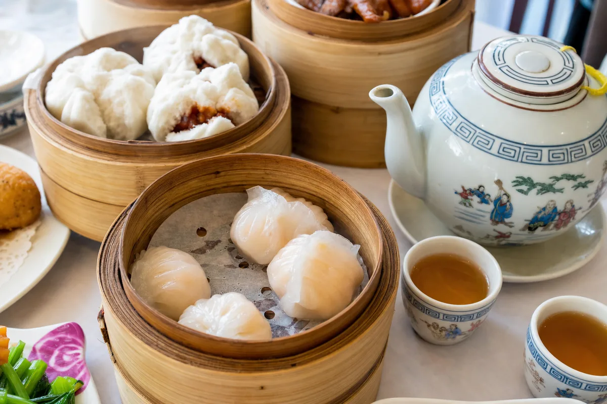 Cantonese dim sum in bamboo steamers with shrimp dumplings and a pot of tea