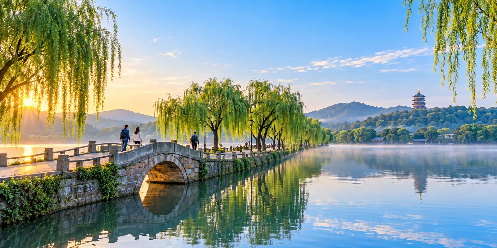 The Su Causeway on West Lake in Hangzhou at early morning, willow trees along the path and Leifeng Pagoda in the distance