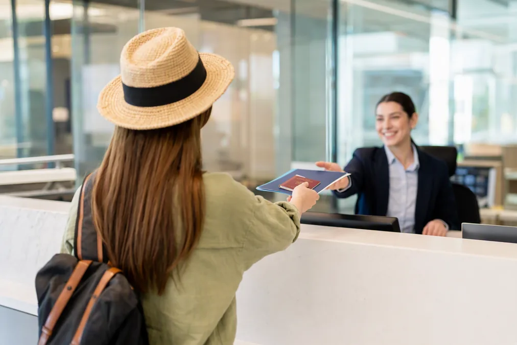 Person handing a passport and documents across a service counter