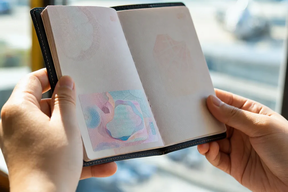 Hands holding an open passport checking a visa page