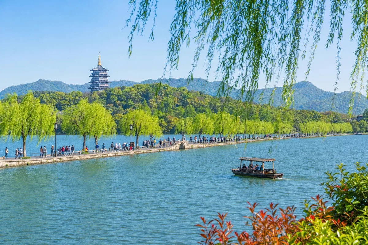 West Lake in Hangzhou with the Su Causeway, willows, and a boat on the water
