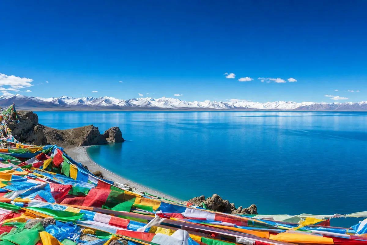 Turquoise water of Namtso Lake backed by snow mountains in Tibet