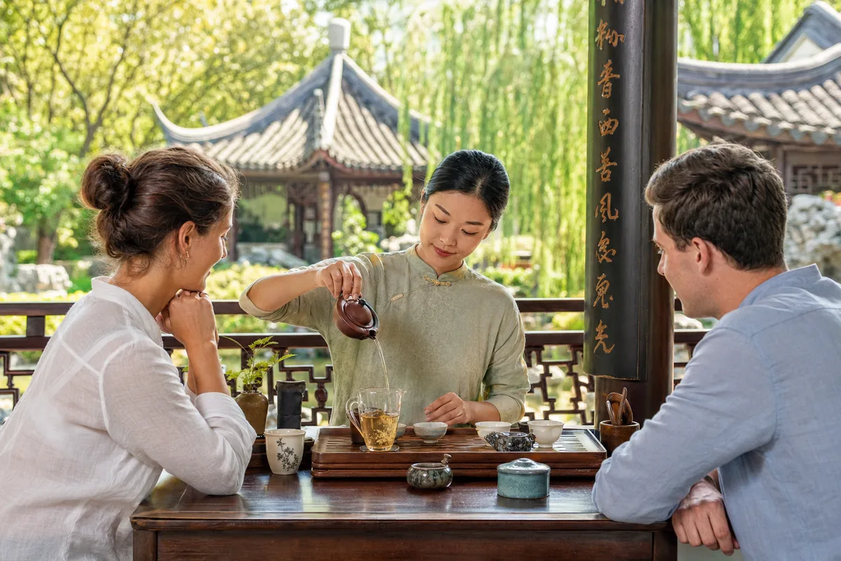 Private Chinese tea ceremony in a garden pavilion with a tea master pouring loose-leaf tea