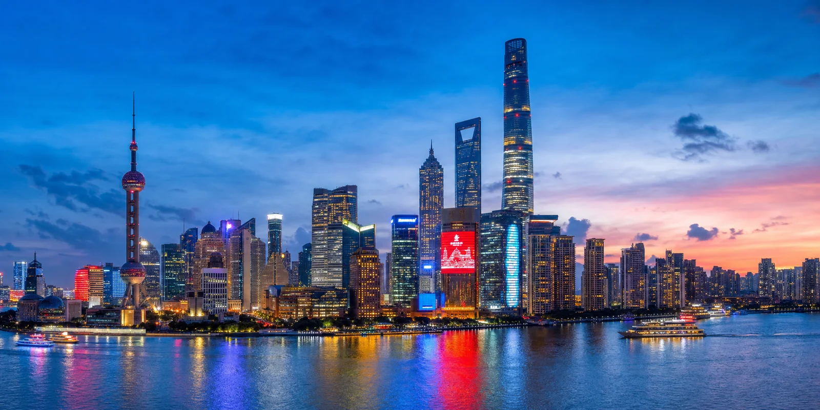 Shanghai skyline at dusk showing Shanghai Tower, World Financial Center and Jin Mao Tower over the Huangpu River
