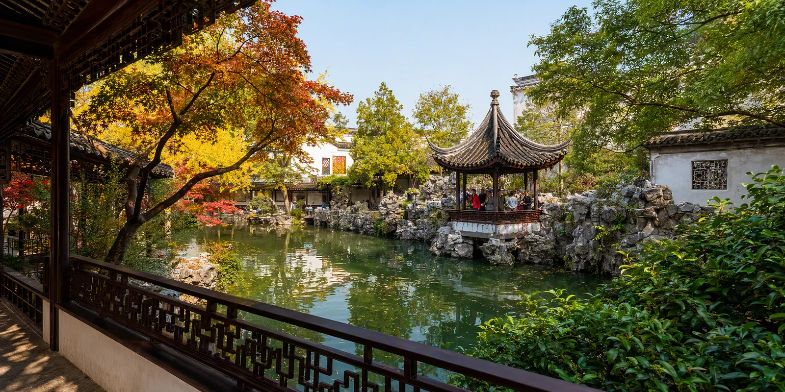Visitors in a pavilion overlooking rockeries and a pond in a classical Suzhou garden