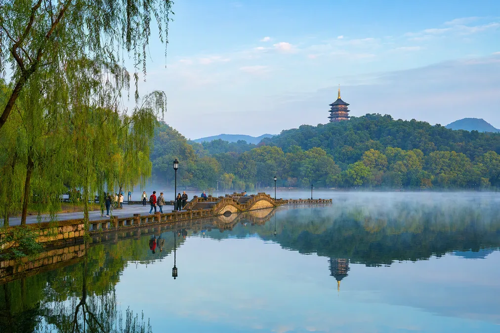 Early morning on West Lake's east shore in Hangzhou with a pagoda on the wooded hills beyond