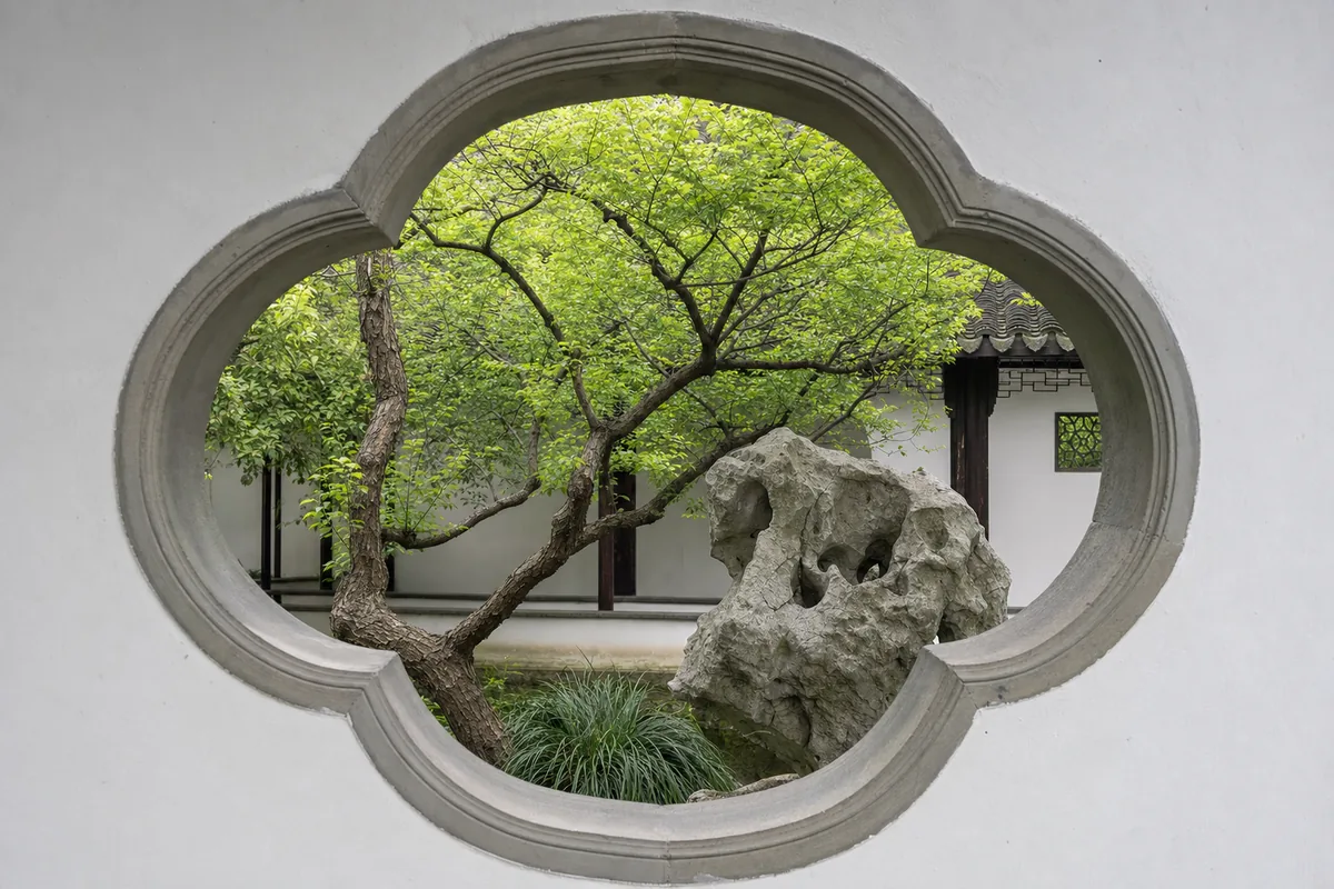 A tree framed through a carved garden window in the Humble Administrator's Garden in Suzhou