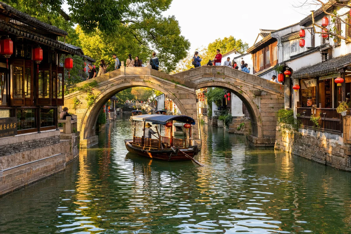 Stone arch bridge over a canal lined with old whitewashed houses and a boat in Zhouzhuang water town near Suzhou