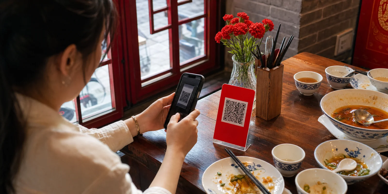 Diner scanning a QR code with a phone to pay a restaurant bill in China, showing cashless payment with no tip line