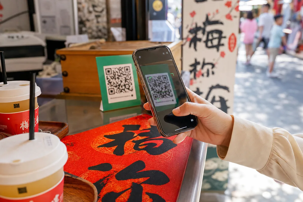 Hand scanning a QR code with a smartphone to pay in China, illustrating QR code phishing risk