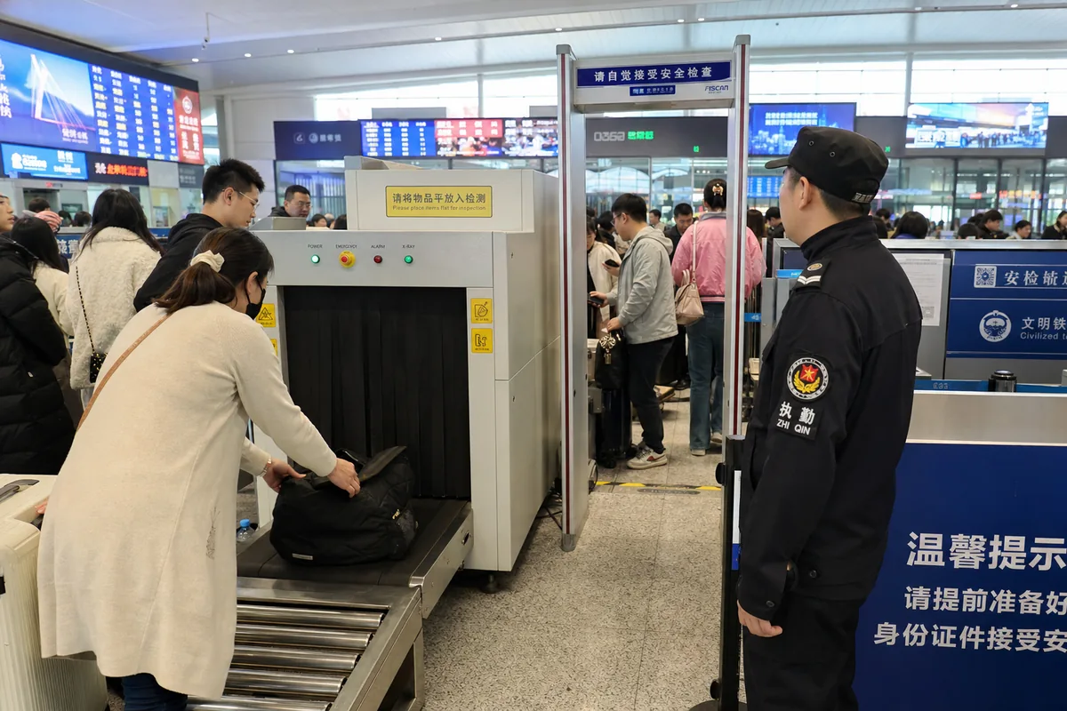 Security screening area at a Chinese train station entrance with X-ray belt and metal detector gate