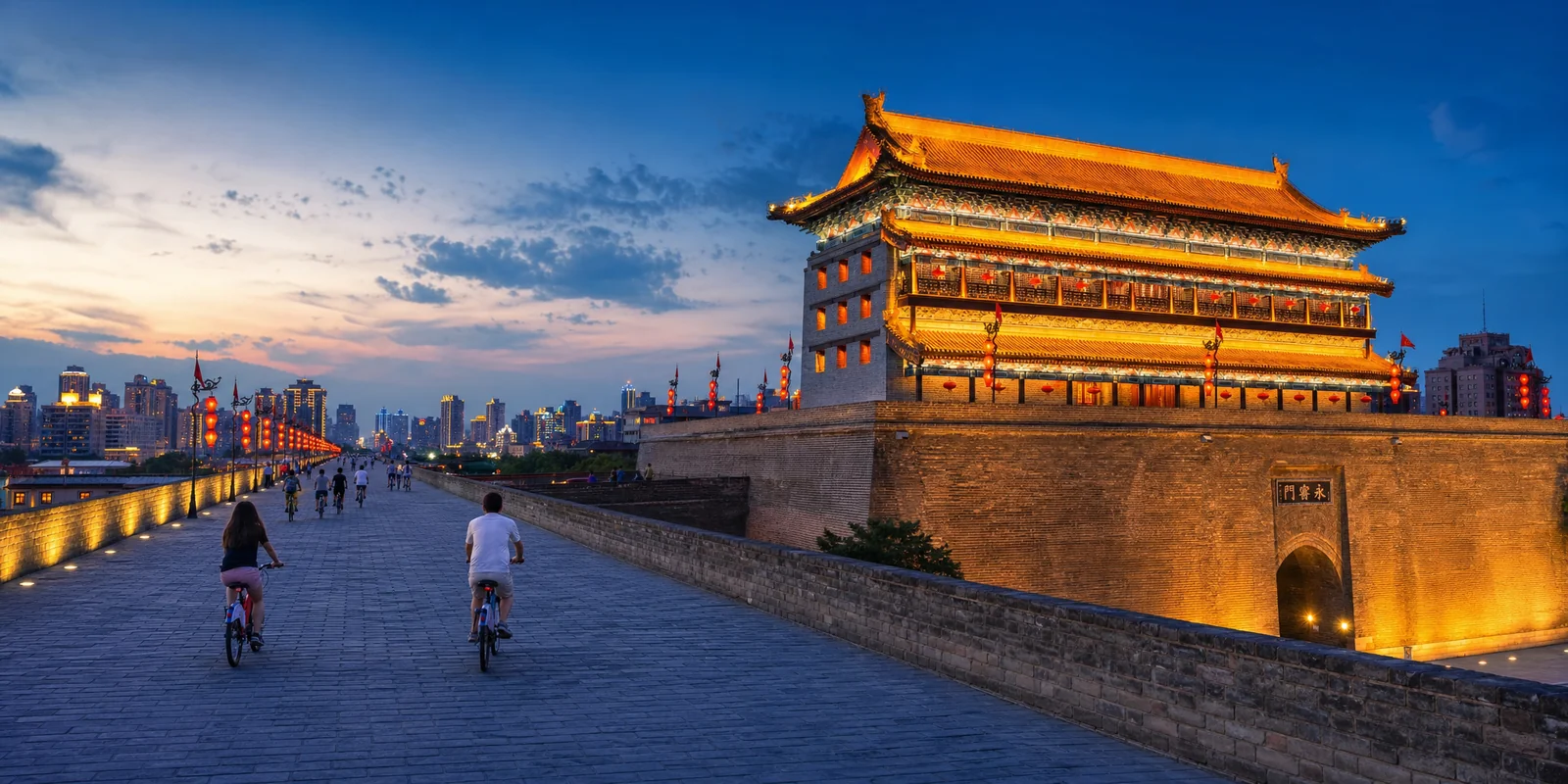 Xi'an City Wall South Gate lit up at dusk with the ancient gate tower above and the modern city beyond