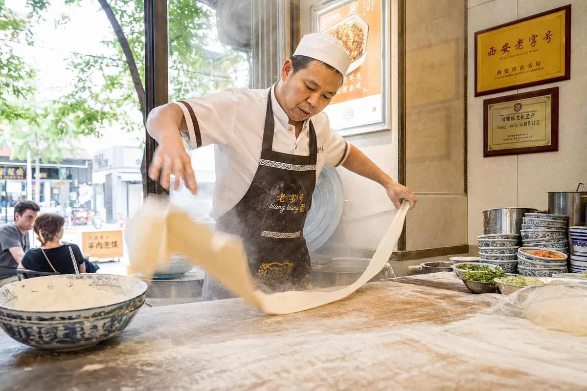 Cook hand-pulling and slapping wide biangbiang noodles against the counter
