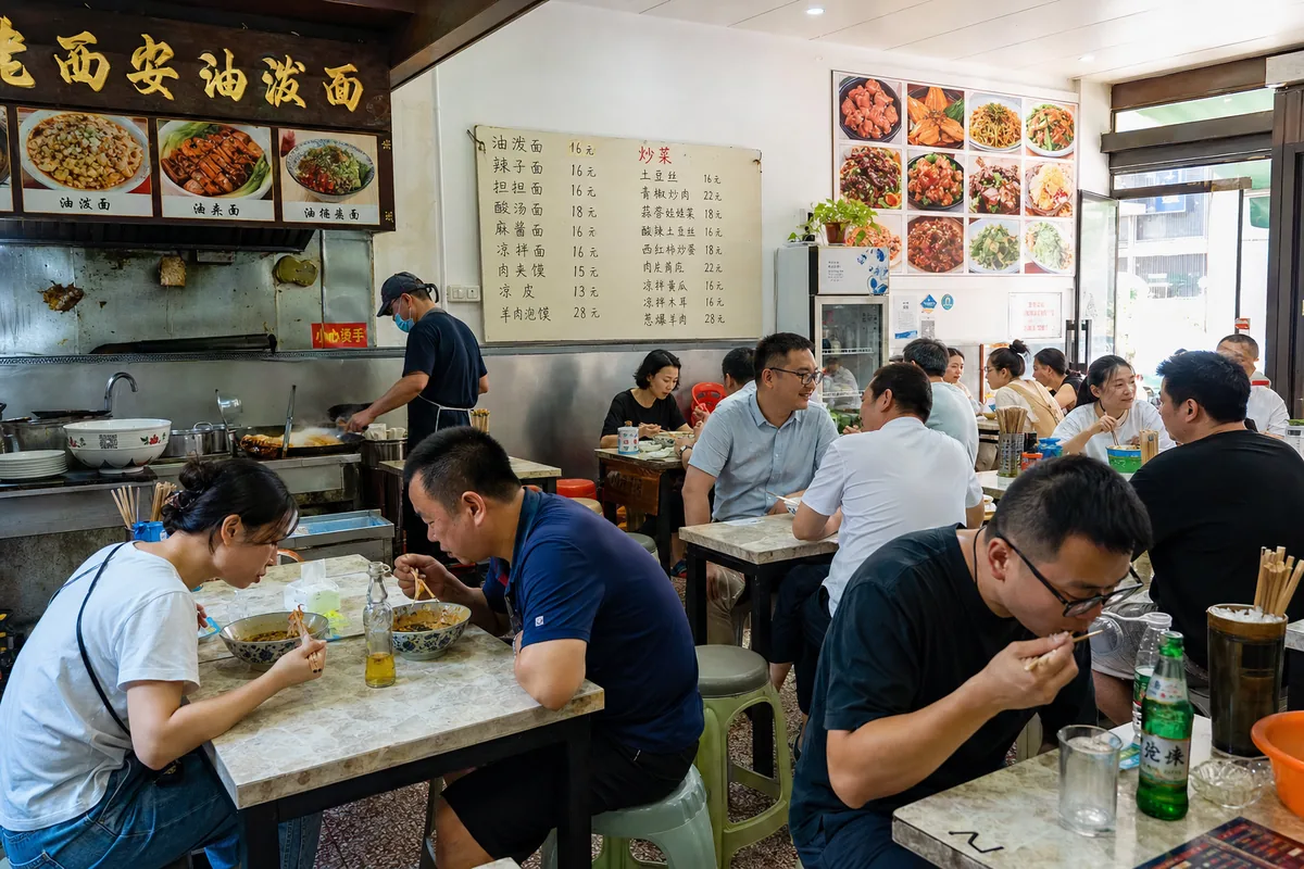 Small local noodle shop in Xi'an packed with lunchtime diners on plastic stools