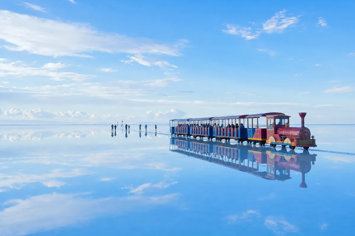 Chaka Salt Lake mirror reflection of the sky with a small tourist train on the salt flat