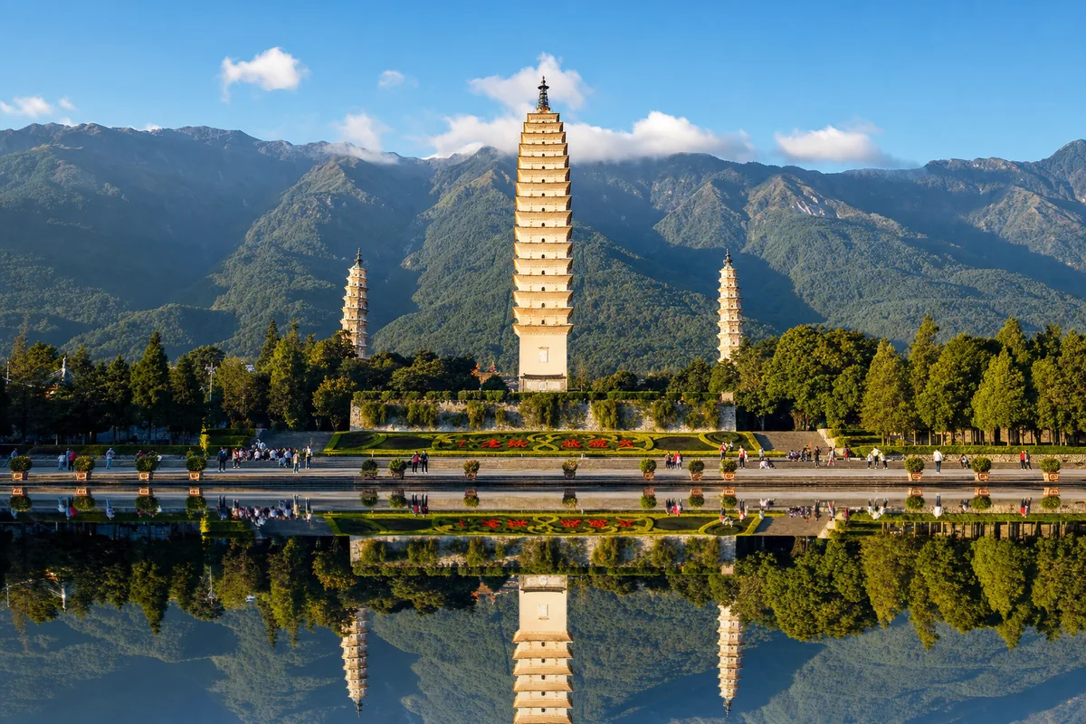 The Three Pagodas of Dali reflected in a pond with Cangshan mountains behind